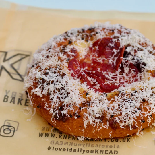 Round pastry topped with grated cheese and cured meat slices