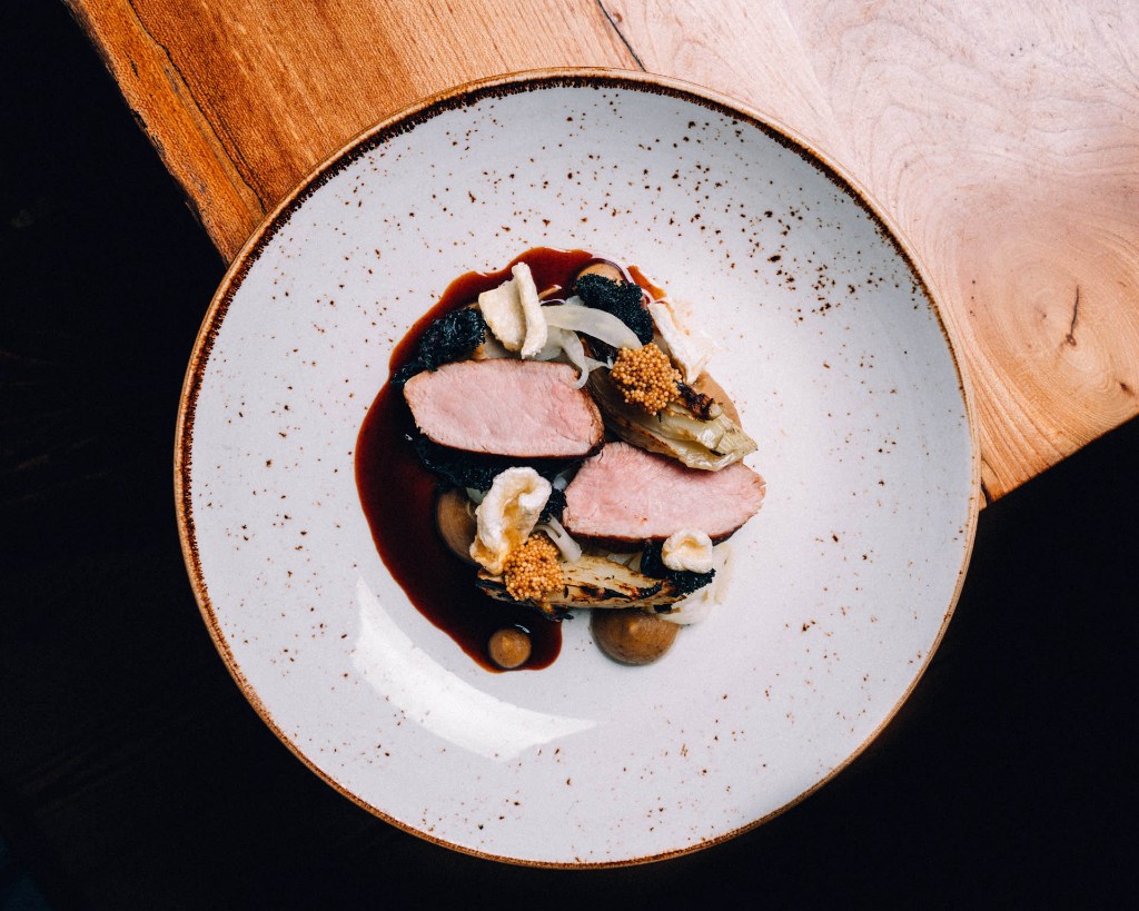 Overhead view of a fine-dining plate with protein and garnish