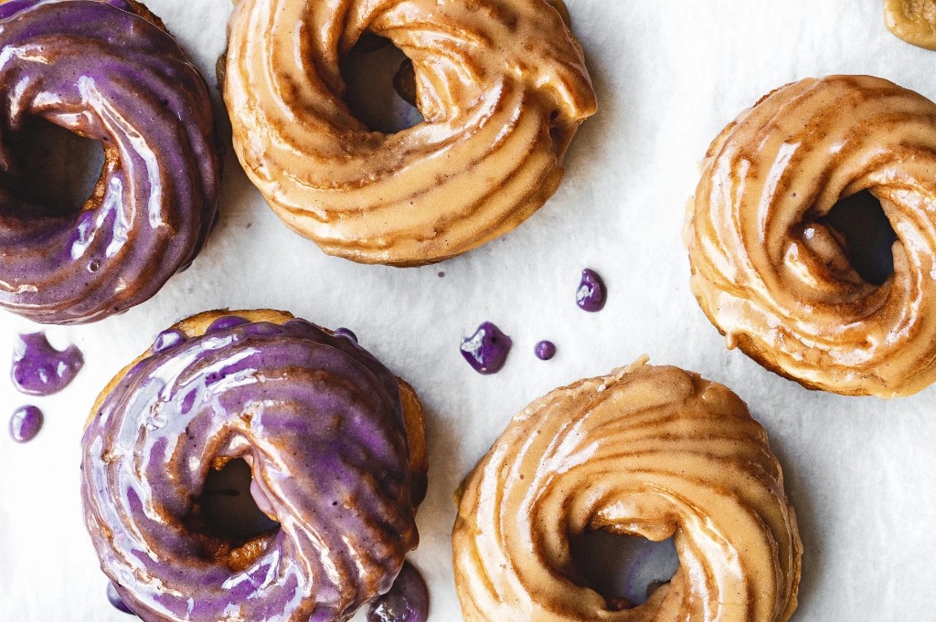 Purple and maple-glazed cruller donuts on parchment