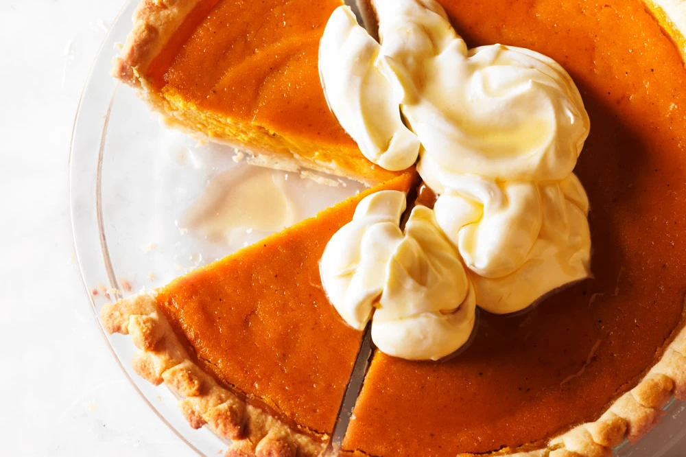 Pumpkin pie with whipped cream and one slice removed