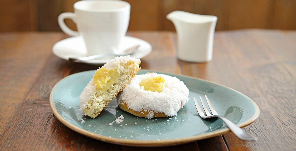 Coconut-topped bun with custard centre on a teal plate