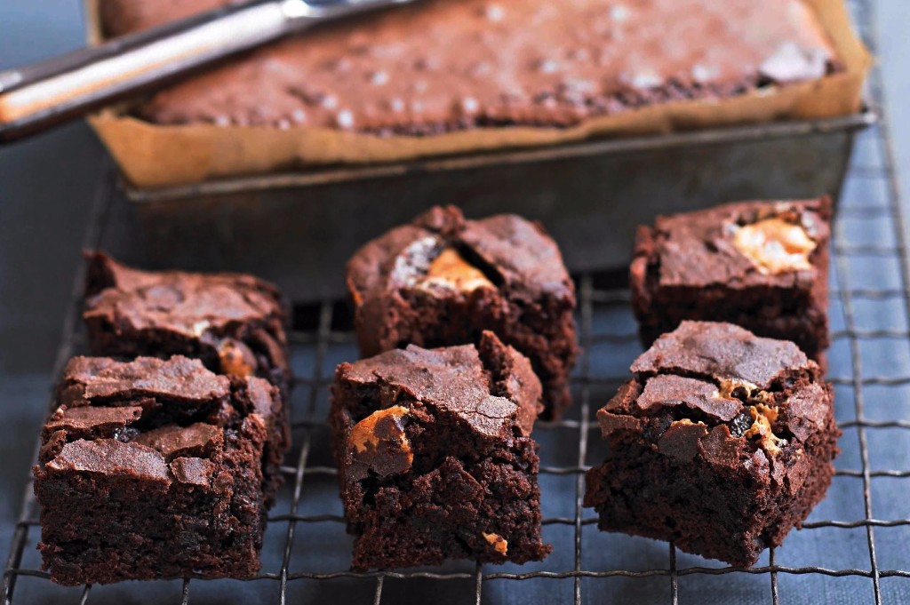 Fudgy brownies on a cooling rack with baking tin behind